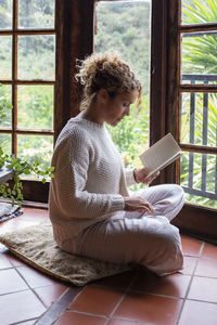 Young woman using mobile phone while sitting at home