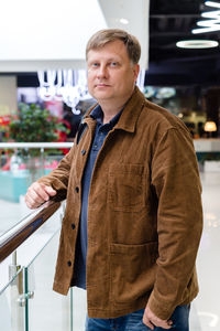 Portrait of young man standing by railing