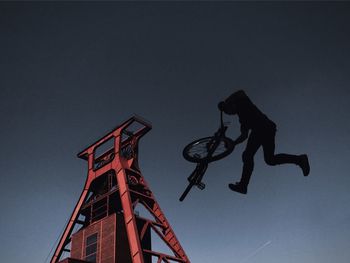 Low angle view of biker performing stunt against tower