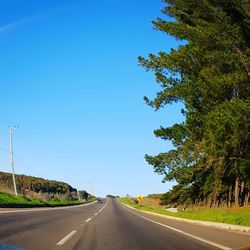 Empty road against clear blue sky