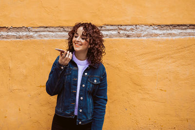 Young woman standing against wall