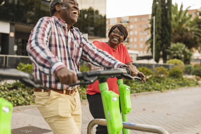 Happy senior couple spending leisure time with push scooters