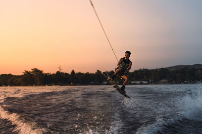 Latino mas doing wakeboarding in a lake with mountains in the background