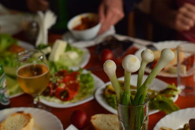 Spring onions in glass with food in plates on table