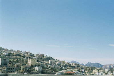 Buildings in city against clear blue sky