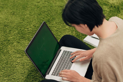 High angle view of woman using laptop while sitting on grass