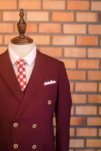 Close-up of red suit in display against brick wall