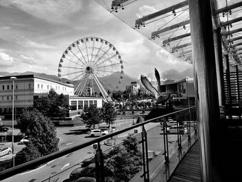 Ferris wheel in city against cloudy sky