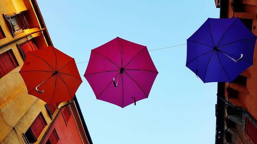 Low angle view of umbrellas against clear blue sky