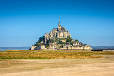 Castle by sea against clear blue sky