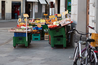 Fruit and vegetable stand displayed outside of a small retailer on a street in the city, italy.