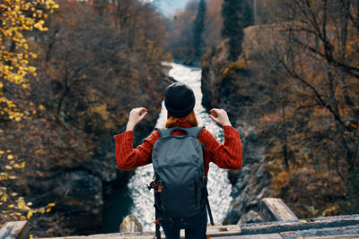 Rear view of man standing by trees during autumn