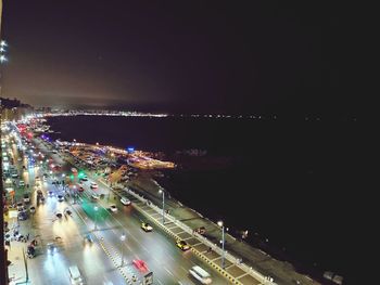 High angle view of illuminated city by sea against sky