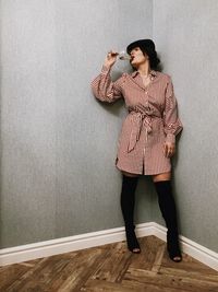 Woman drinking wine while standing against wall