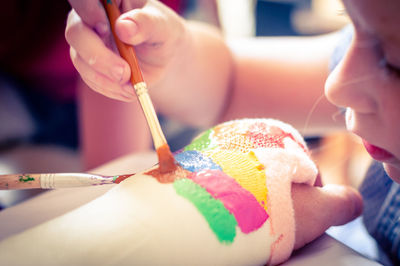 Close-up of girl painting bandage while sitting at home