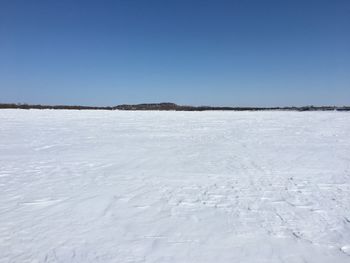 Surface level of frozen lake against clear blue sky