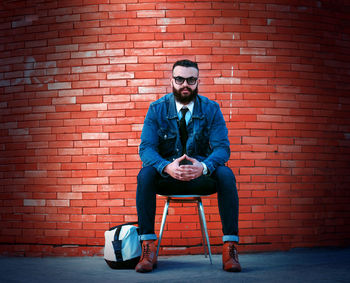 Portrait of man sitting on brick wall