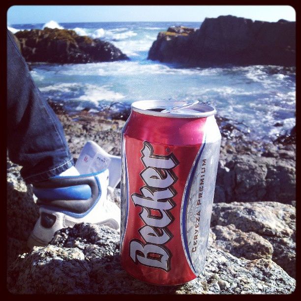 transfer print, water, sea, auto post production filter, red, rock - object, text, close-up, focus on foreground, outdoors, day, communication, shore, beach, part of, metal, western script, mountain, one person, nature