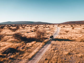 Road leading towards mountains against clear sky