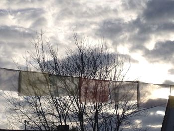 Low angle view of bare tree against cloudy sky