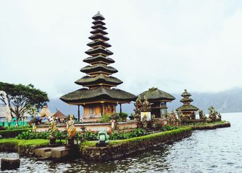 Temple building by lake against sky