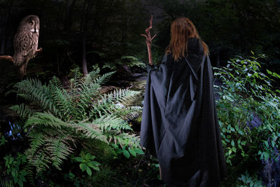 Woman standing by trees in forest