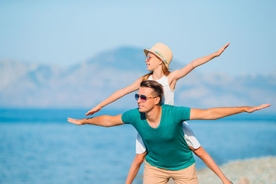 Woman with arms raised standing against sea