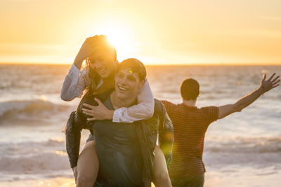 Group of teenagers having fun on beach at sunset