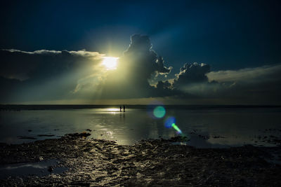 Sunlight streaming on sea against sky
