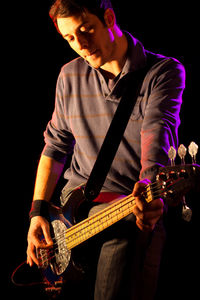 Man playing guitar while standing in dark