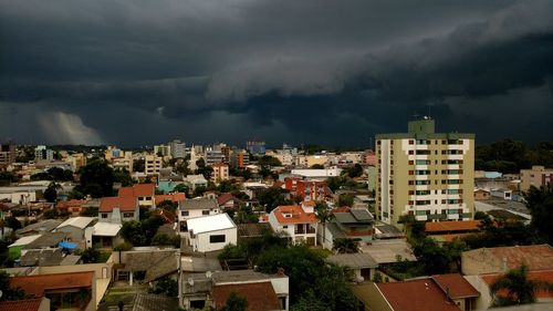 High angle view of buildings in city against storm clouds