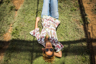 High angle view of mature woman lying on grassy field during sunny day