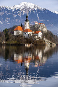 Reflection of chapel in lake against snowcapped mountain