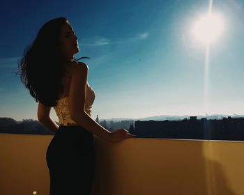 Rear view of woman standing by retaining wall against sky