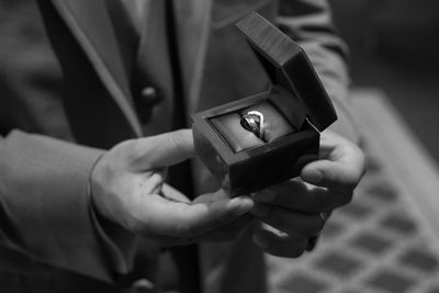 Midsection of man holding wedding ring