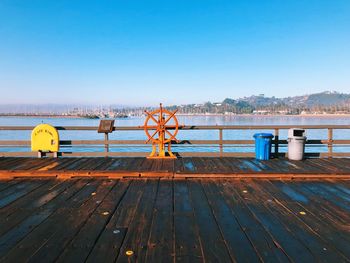 Pier over lake against clear blue sky