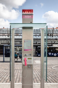 Information sign on footpath against sky in city