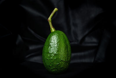 Close-up of green lemon on table against black background