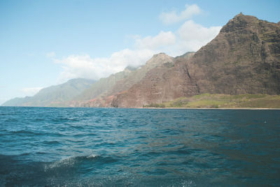 Scenic view of sea by mountains against sky