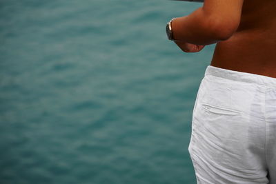 Midsection of young woman standing by sea