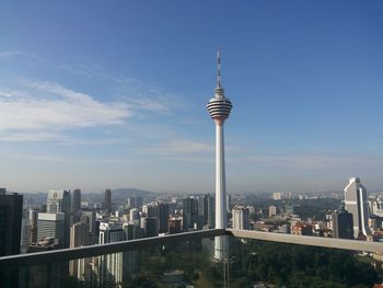 Communications tower in city against sky