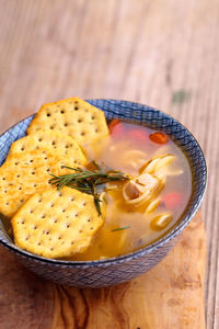 Close-up of chicken noodle soup with crackers in bowl on cutting board