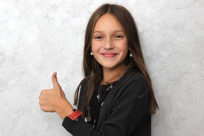 Portrait of smiling girl gesturing against wall