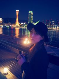Portrait of woman against illuminated city at night