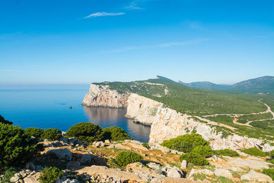 Scenic view of sea and mountains against blue sky