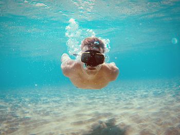 Portrait of shirtless young man swimming undersea