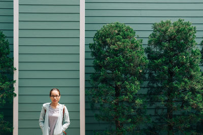 Portrait of woman standing against green wall