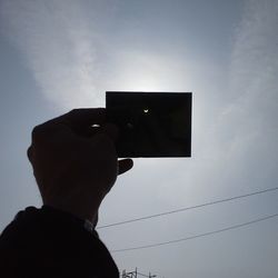 Low angle view of photographer photographing against sky