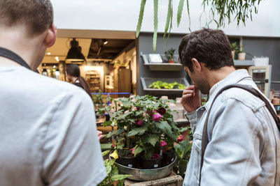 Man discussing with male owner over potted plants at store