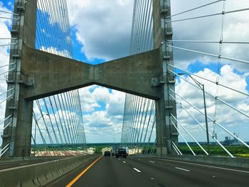 Road passing through city against cloudy sky